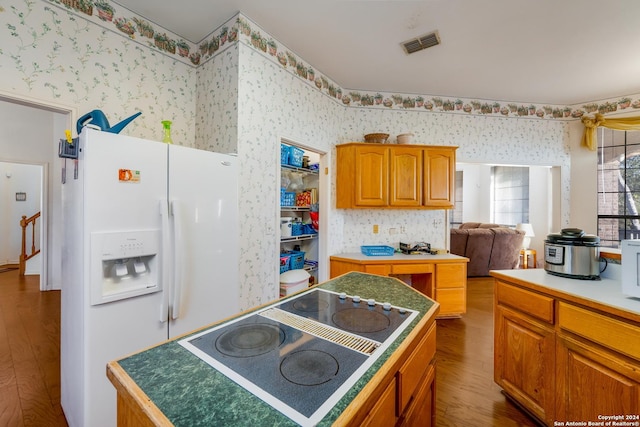 kitchen with electric cooktop, a kitchen island, wood-type flooring, and white refrigerator with ice dispenser