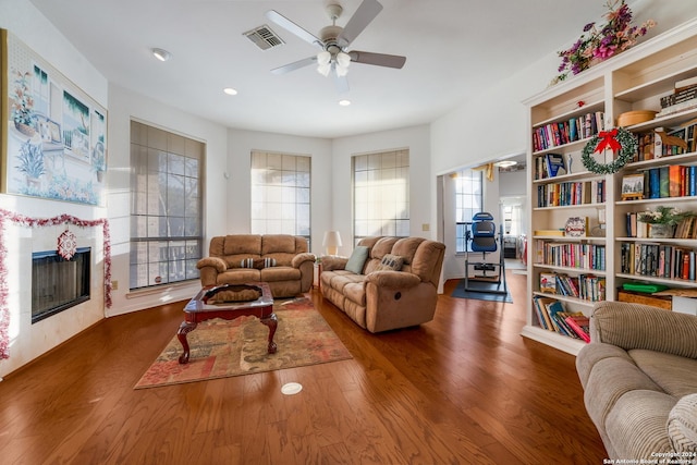 living room with a tile fireplace, dark hardwood / wood-style floors, and ceiling fan