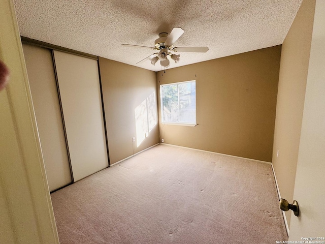 unfurnished room with ceiling fan, light colored carpet, and a textured ceiling