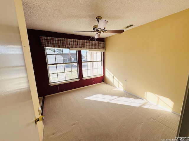 carpeted spare room with ceiling fan and a textured ceiling