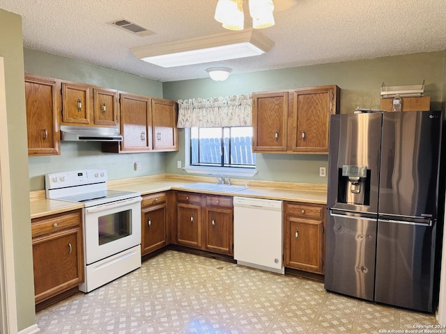 kitchen with a textured ceiling, sink, and white appliances