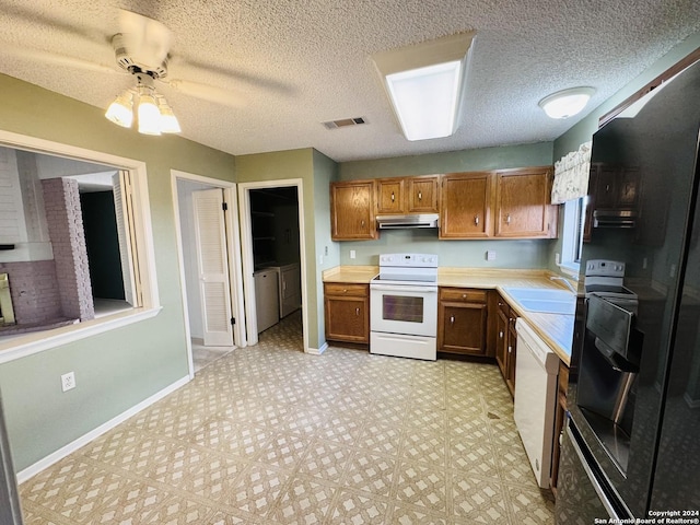 kitchen with ceiling fan, sink, independent washer and dryer, a textured ceiling, and white appliances