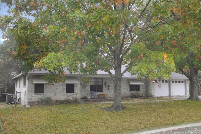 view of front of property featuring a front yard, a garage, and central air condition unit