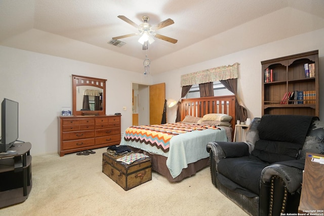 carpeted bedroom with a raised ceiling and ceiling fan