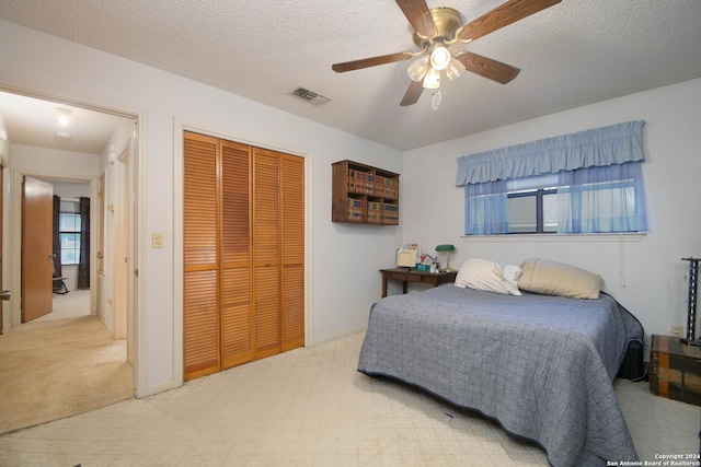 carpeted bedroom featuring a textured ceiling, a closet, and ceiling fan