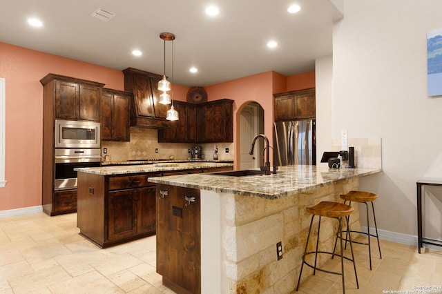 kitchen with sink, hanging light fixtures, stainless steel appliances, kitchen peninsula, and a breakfast bar area