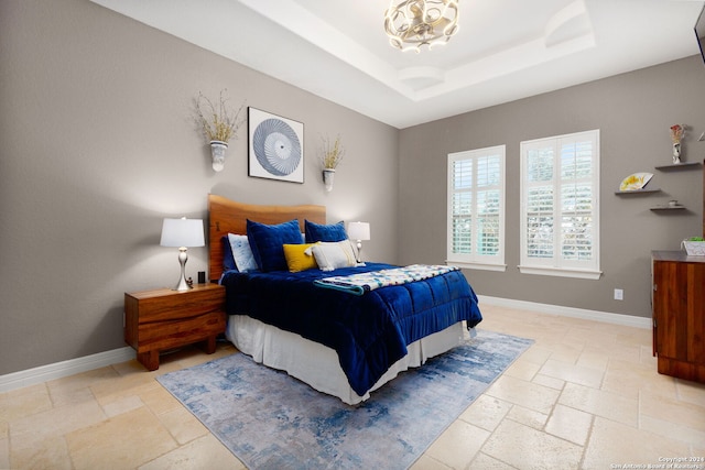 bedroom with a tray ceiling and a chandelier