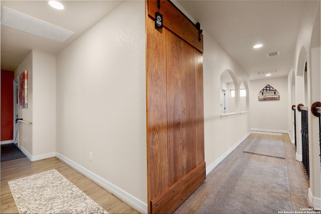 hallway featuring light wood-type flooring and a barn door