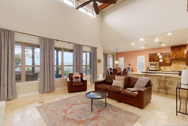 living room featuring ceiling fan, plenty of natural light, and a high ceiling