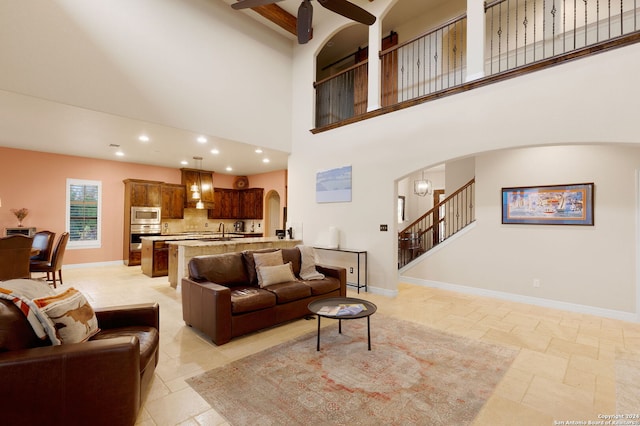 living room featuring a towering ceiling and ceiling fan with notable chandelier