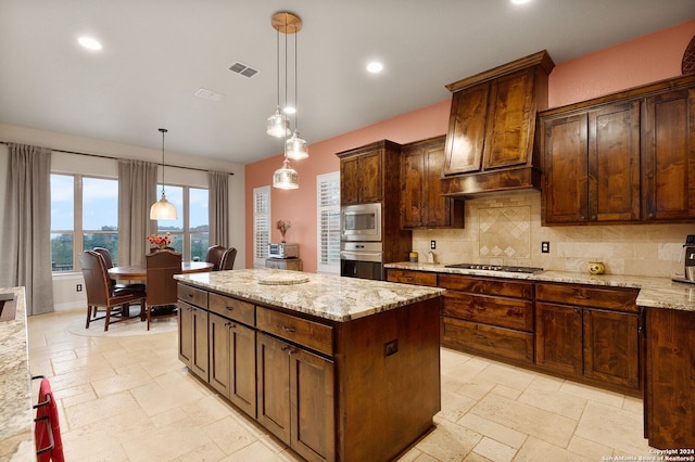 kitchen with light stone countertops, pendant lighting, decorative backsplash, a kitchen island, and appliances with stainless steel finishes