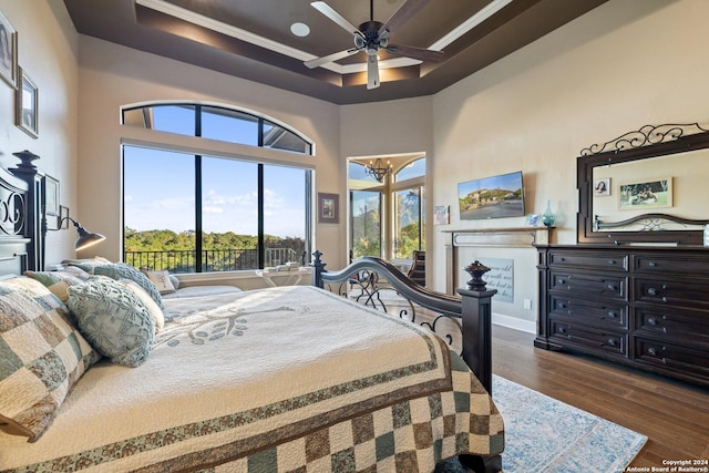 bedroom with ornamental molding, dark hardwood / wood-style floors, ceiling fan, and a tray ceiling