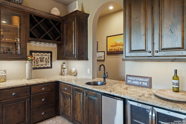 kitchen with dark brown cabinetry, sink, wine cooler, and light stone countertops