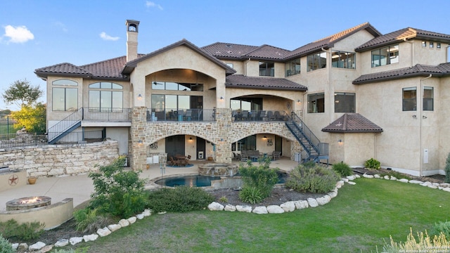 rear view of property featuring a balcony, a yard, a fire pit, and a patio area