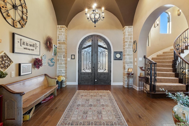 entrance foyer with vaulted ceiling, a notable chandelier, dark hardwood / wood-style flooring, and french doors