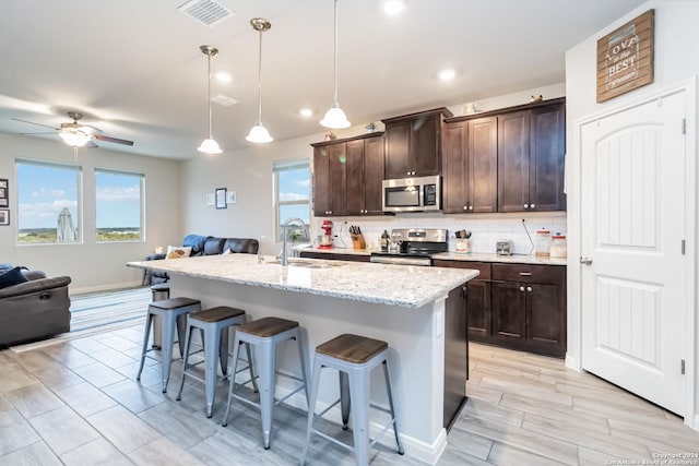 kitchen with a wealth of natural light, pendant lighting, stainless steel appliances, and sink