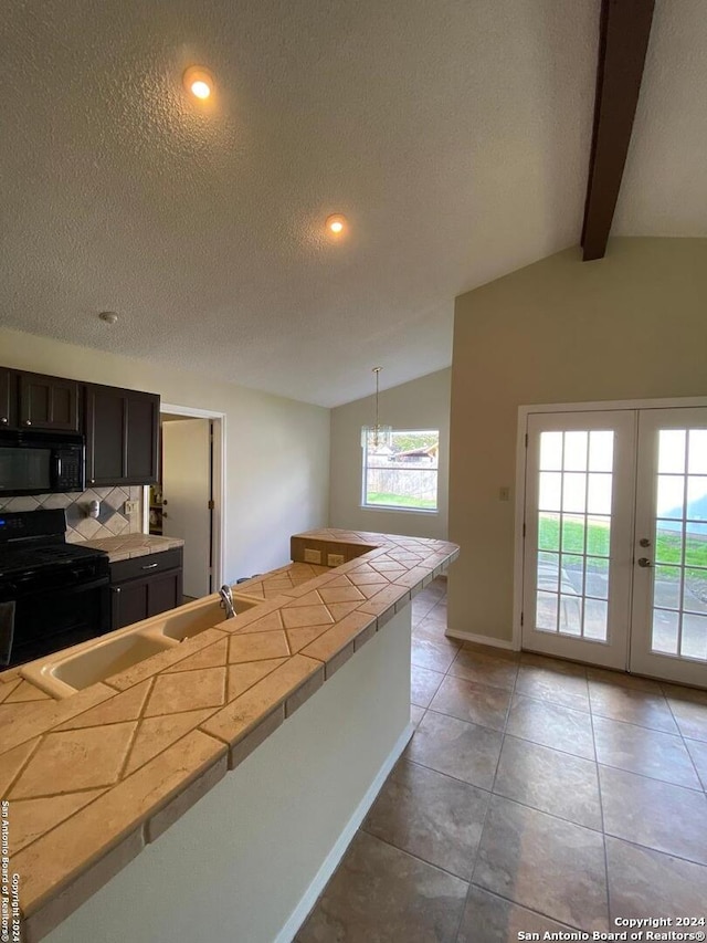 kitchen with pendant lighting, a textured ceiling, black appliances, french doors, and lofted ceiling with beams