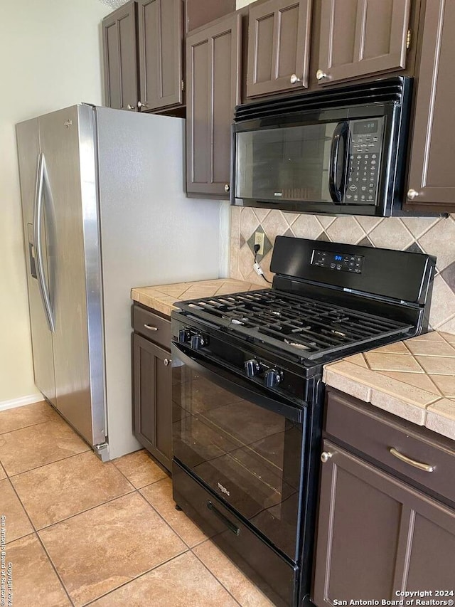 kitchen featuring black appliances, light tile patterned floors, backsplash, and dark brown cabinets