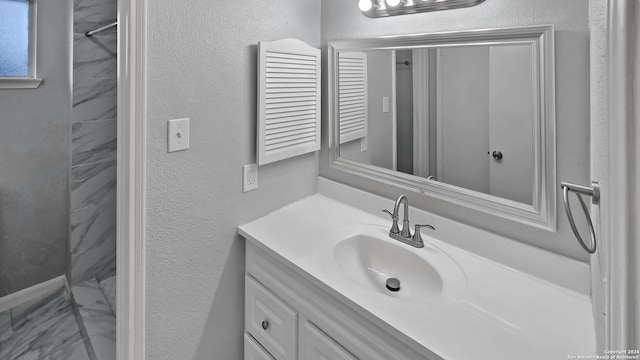 bathroom with a tile shower and vanity