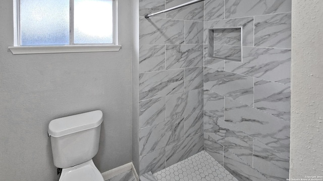 bathroom featuring a tile shower and toilet