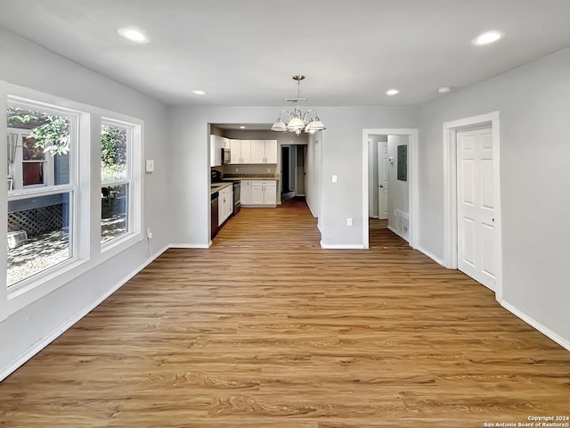 kitchen featuring light hardwood / wood-style flooring, decorative light fixtures, white cabinetry, range, and a chandelier