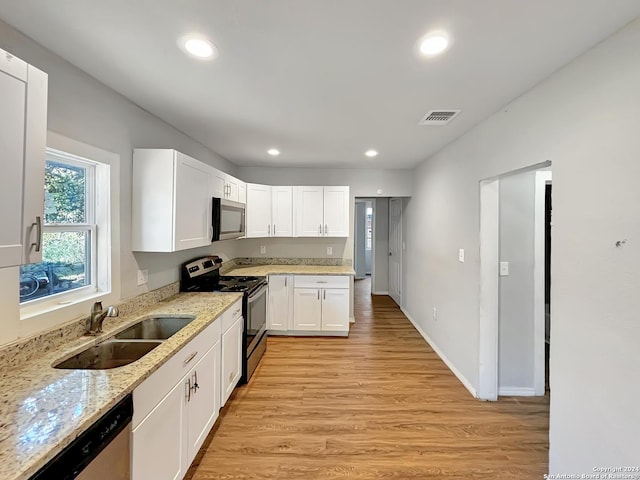 kitchen featuring light stone countertops, stainless steel appliances, sink, light hardwood / wood-style flooring, and white cabinets