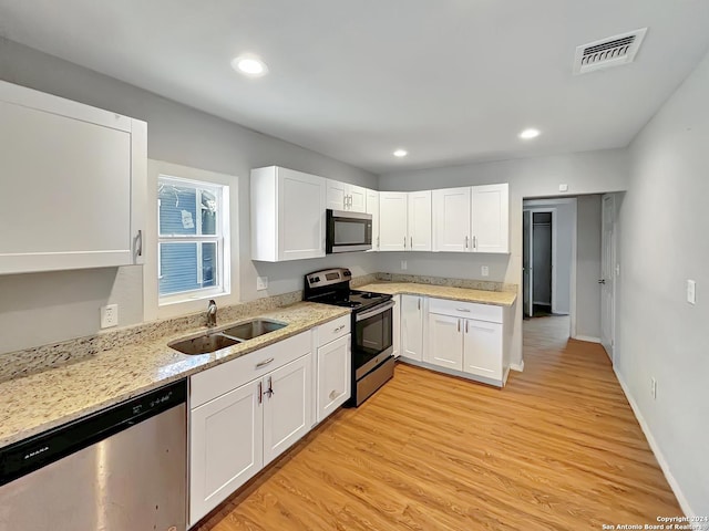 kitchen with white cabinetry, sink, stainless steel appliances, and light hardwood / wood-style flooring