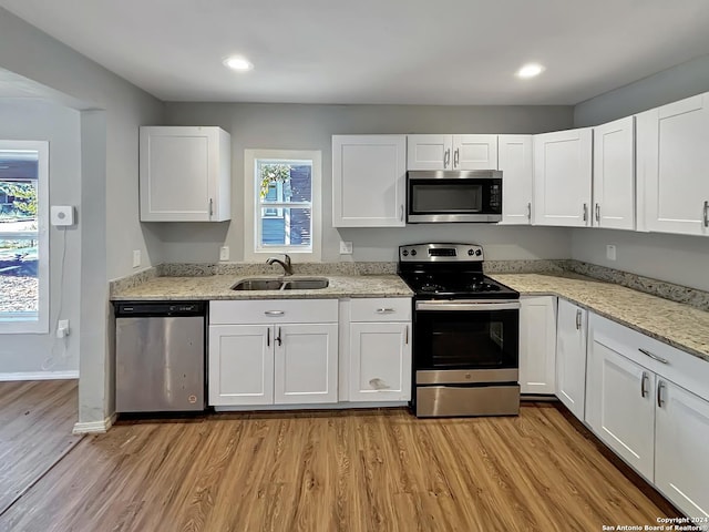 kitchen with light wood-type flooring, white cabinetry, sink, and appliances with stainless steel finishes