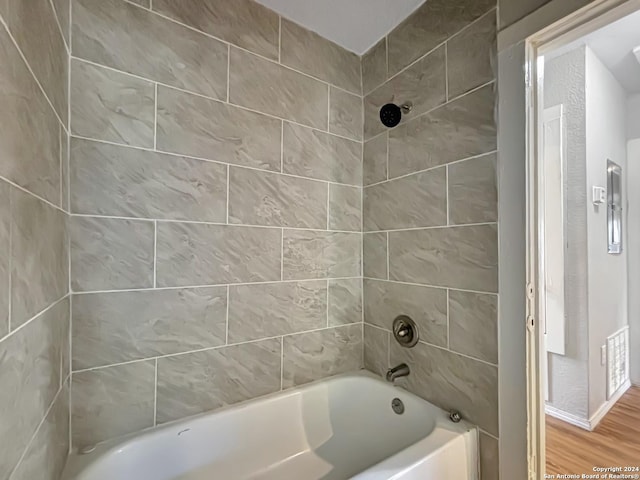 bathroom featuring wood-type flooring and tiled shower / bath