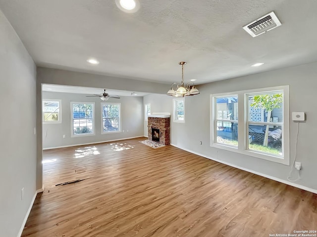 unfurnished living room featuring hardwood / wood-style flooring, ceiling fan with notable chandelier, and a fireplace