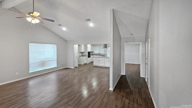 unfurnished living room featuring dark wood-type flooring, high vaulted ceiling, ceiling fan, a textured ceiling, and beam ceiling