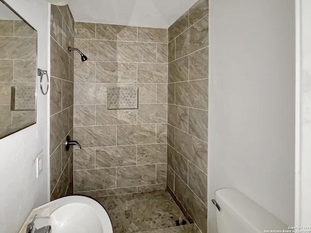 bathroom featuring a tile shower and toilet