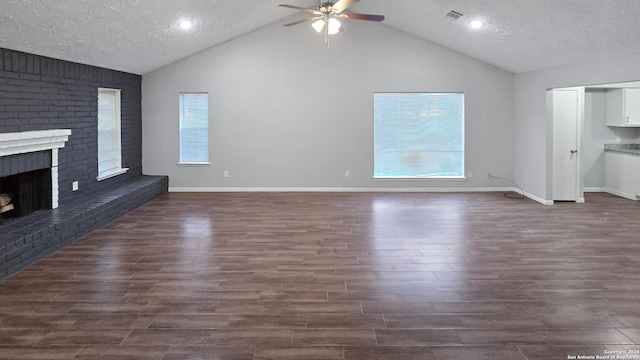 unfurnished living room with dark hardwood / wood-style floors, ceiling fan, a textured ceiling, and a brick fireplace