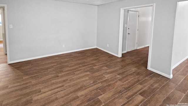 empty room with dark hardwood / wood-style floors and a textured ceiling