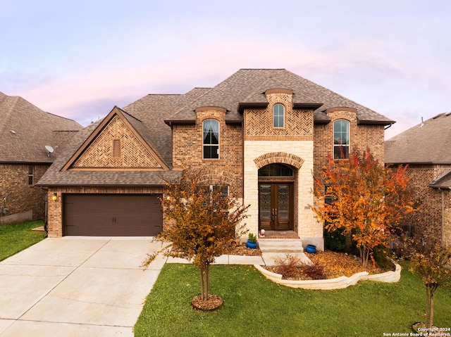 french country inspired facade with a lawn, a garage, and french doors