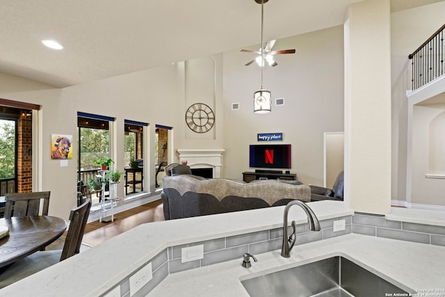 kitchen featuring light stone countertops, ceiling fan, sink, high vaulted ceiling, and dark hardwood / wood-style floors