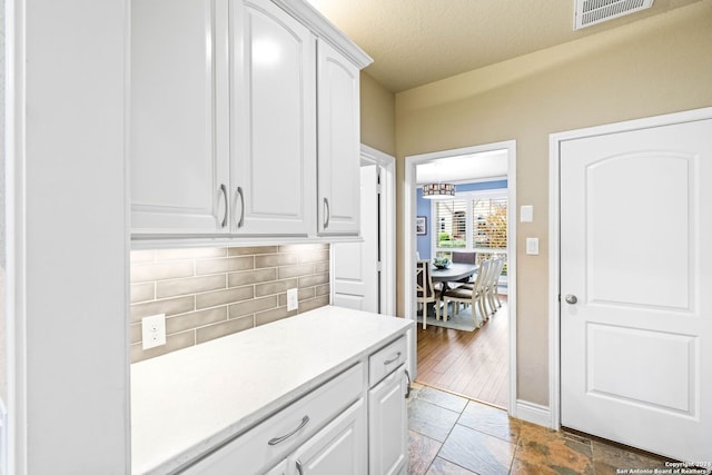 kitchen with backsplash, white cabinets, a textured ceiling, and hardwood / wood-style flooring