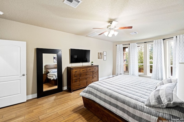 bedroom featuring ceiling fan, light hardwood / wood-style flooring, and a textured ceiling