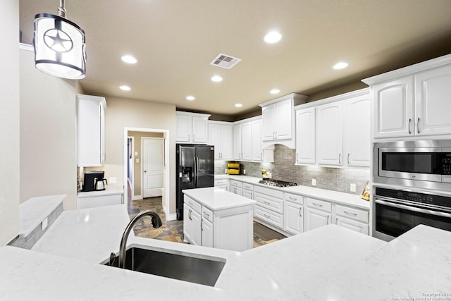 kitchen with light stone countertops, stainless steel appliances, sink, decorative light fixtures, and white cabinets