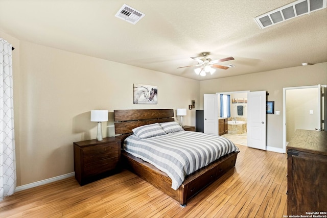 bedroom with ceiling fan, light hardwood / wood-style flooring, ensuite bathroom, and a textured ceiling