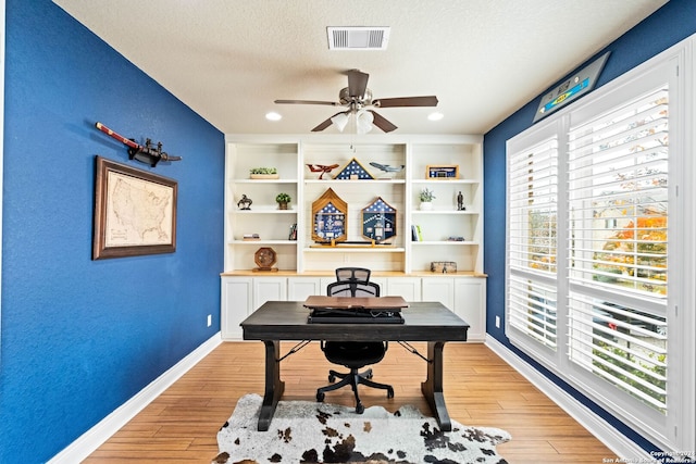 office featuring ceiling fan, light hardwood / wood-style floors, and a textured ceiling