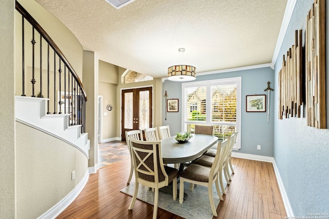 dining space with french doors, a textured ceiling, and light wood-type flooring