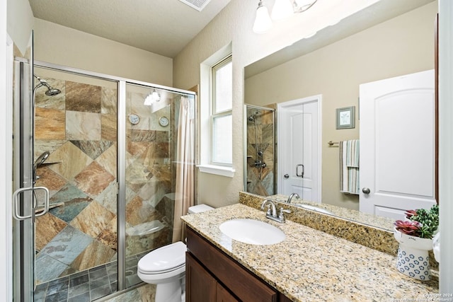 bathroom with vanity, a shower with door, toilet, and plenty of natural light