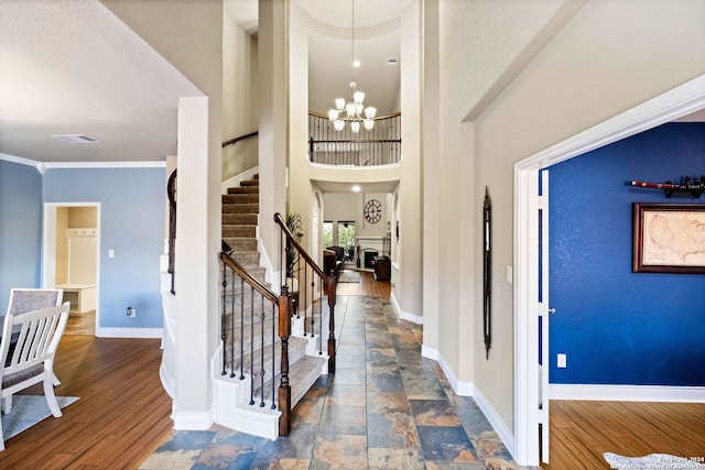 entryway with a high ceiling, dark hardwood / wood-style floors, an inviting chandelier, and crown molding