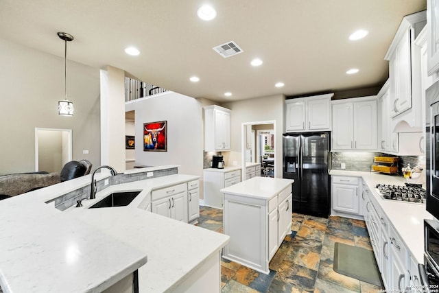 kitchen with white cabinets, stainless steel gas stovetop, a center island, and black refrigerator with ice dispenser