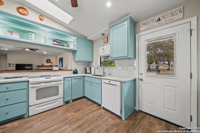 kitchen featuring tasteful backsplash, white appliances, lofted ceiling with skylight, sink, and hardwood / wood-style flooring