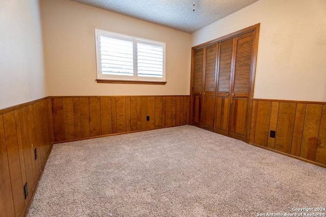 unfurnished bedroom featuring wood walls, a closet, and a textured ceiling