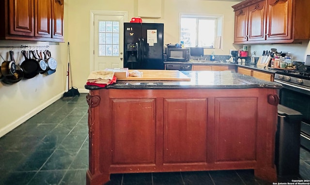 kitchen with a kitchen island, dark tile patterned floors, and black appliances