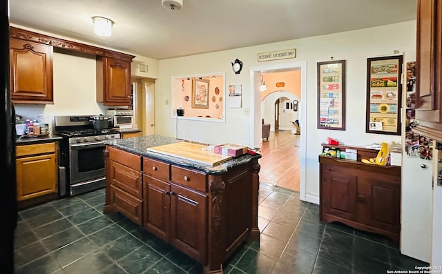 kitchen with a kitchen island, dark wood-type flooring, and stainless steel gas range