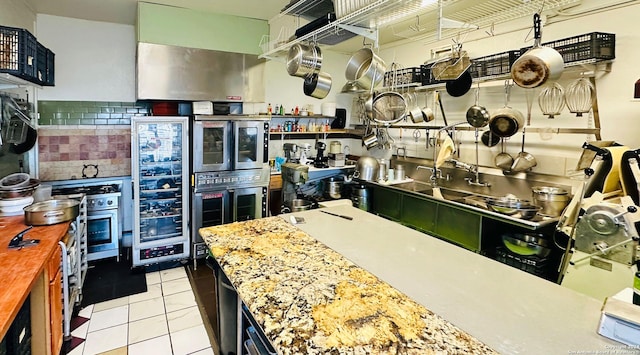 kitchen featuring stainless steel oven, light tile patterned floors, wine cooler, and tasteful backsplash